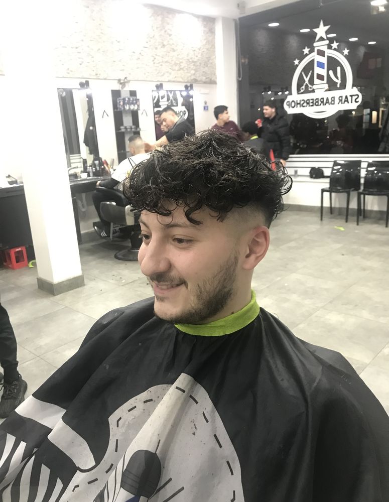 Client with a curly top and tapered sides in the Star Barbershop salon