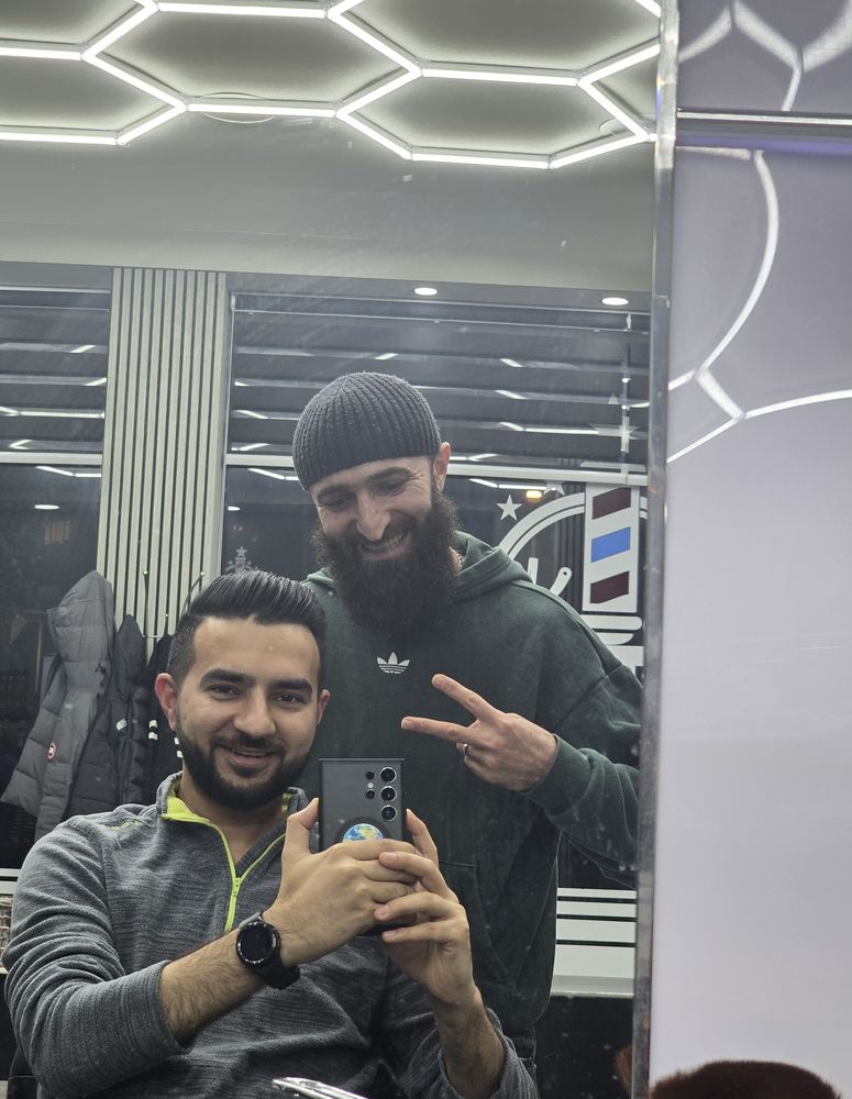 Mirror shot of a client and his barber after a fresh cut and beard trim