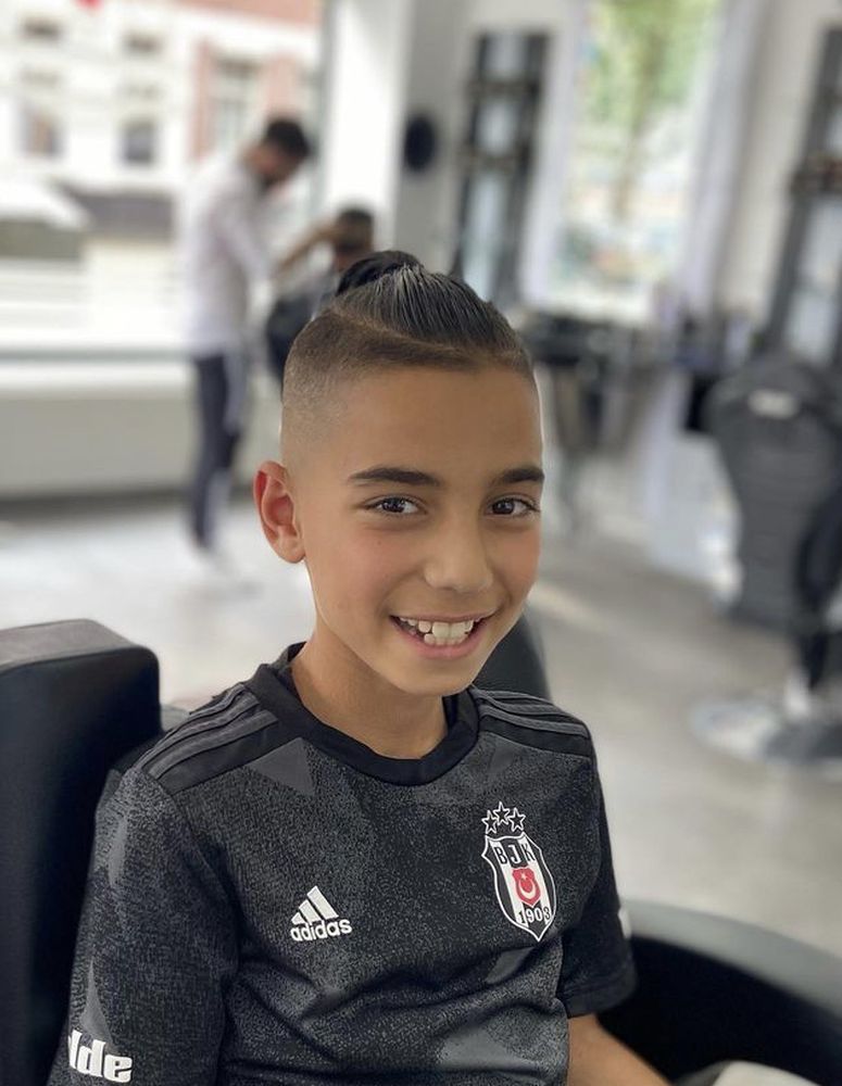 Young client with a high fade and textured top, smiling in the chair