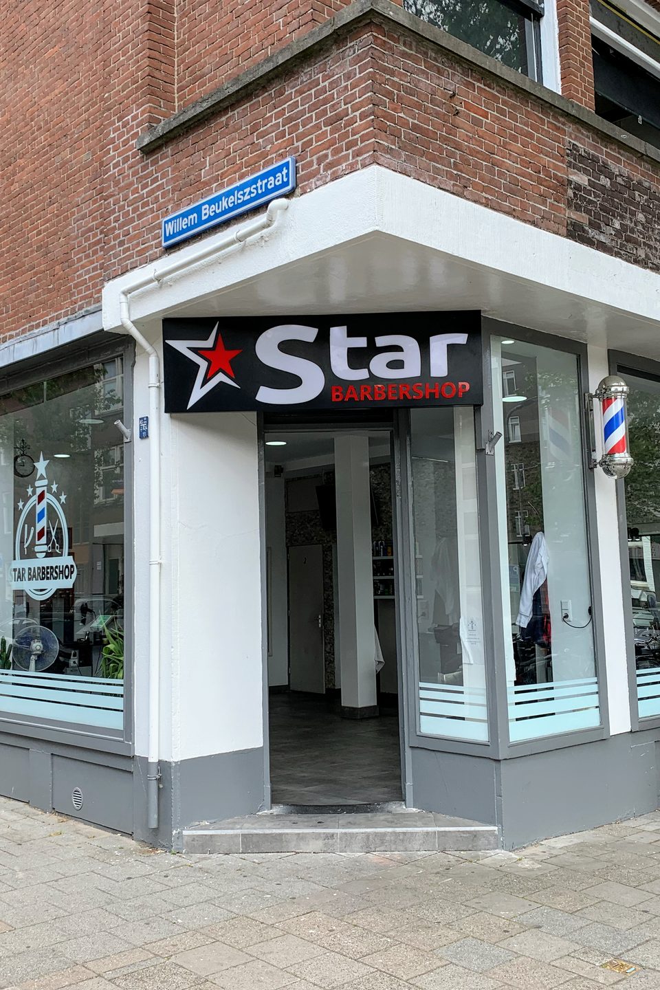 Star Barbershop's corner storefront in Rotterdam, with its illuminated sign, barber pole and glass frontage